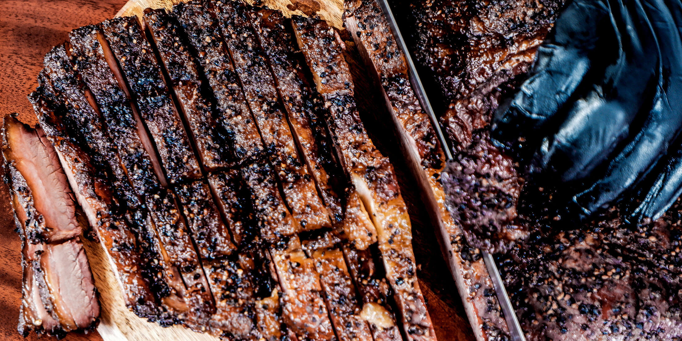 Sliced peppered smoked brisket on a wood board