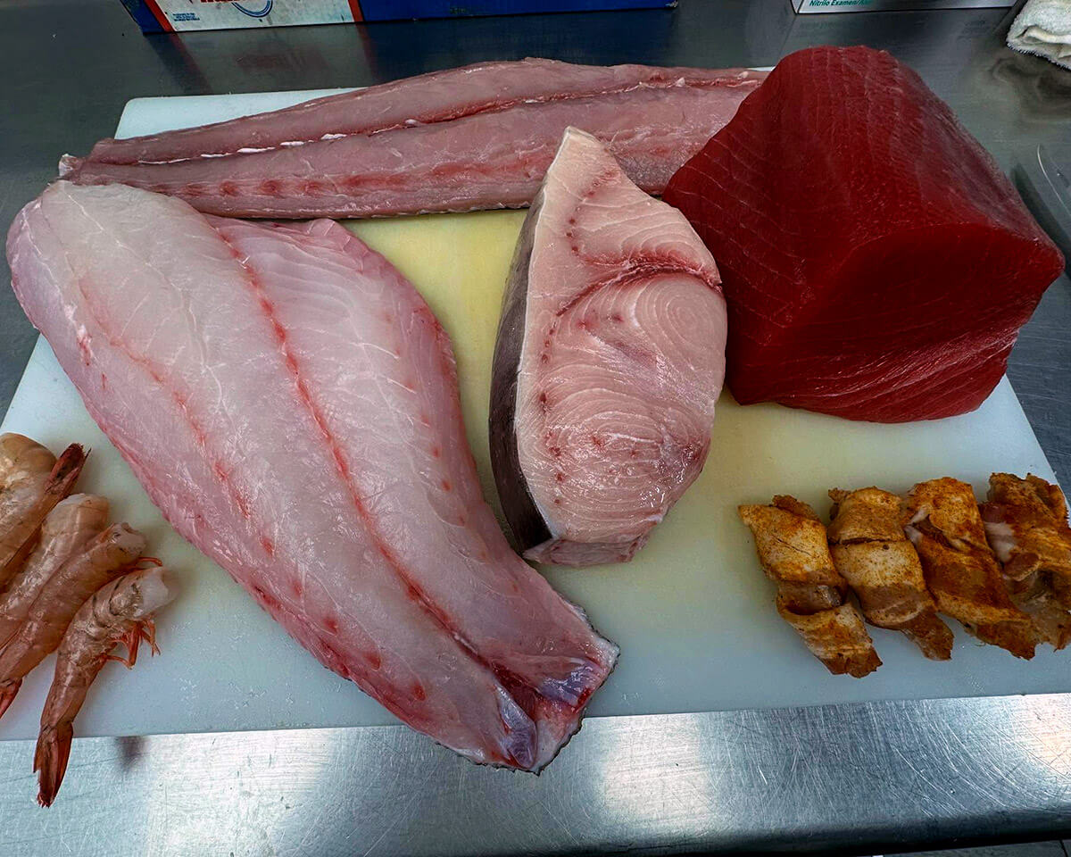 Fresh tuna, swordfish, snapper and shrimp on a cutting board